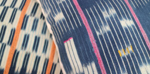 Close-up of blue and white patterned fabric with pink and orange stripes.